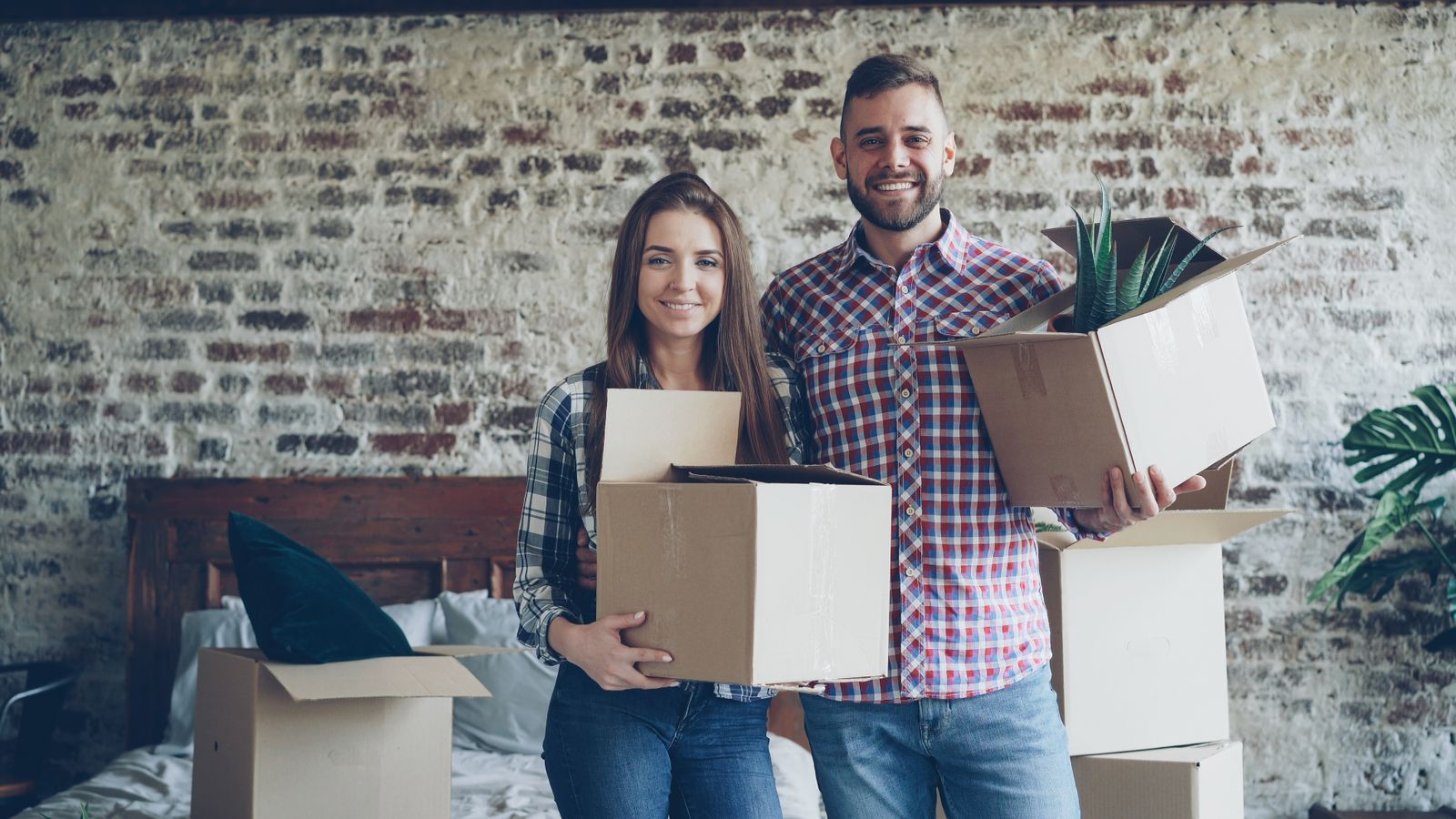 Couple holding boxes in a new home